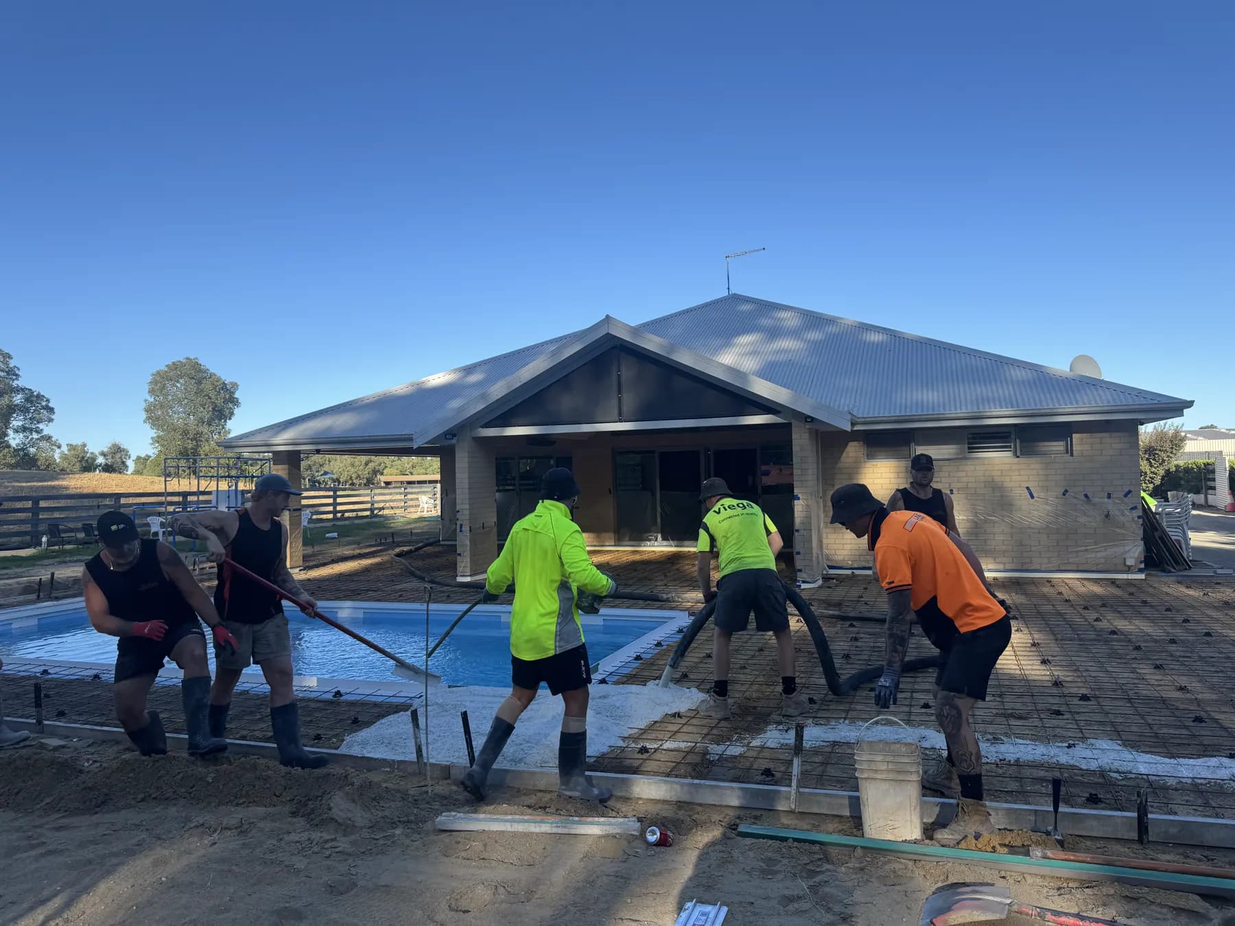 Concrete crew pumping concrete around a pool surround